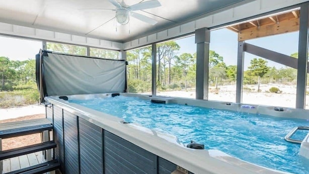 A hot tub with a wooden deck and a view of the surrounding landscape.