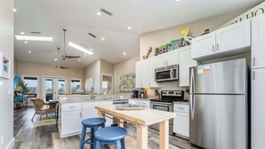 A modern kitchen with white cabinets, stainless steel appliances, and a wooden island with stools.