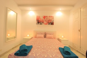 Une chambre d’hôtel avec un grand lit, deux tables de chevet avec des lampes, un tableau au mur et une armoire.