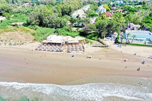 A beach with a building that has multiple lounge areas and a pool. - 1094 Luxurious Golden Beach Duplex Penthouse (Marbella)