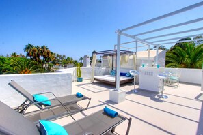 A rooftop terrace with lounge chairs, a small bed, and a bar area. - 1094 Luxurious Golden Beach Duplex Penthouse (Marbella)