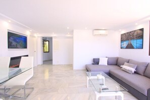 A modern living room with a sofa, a glass coffee table, and artwork on the walls. - 1094 Luxurious Golden Beach Duplex Penthouse (Marbella)