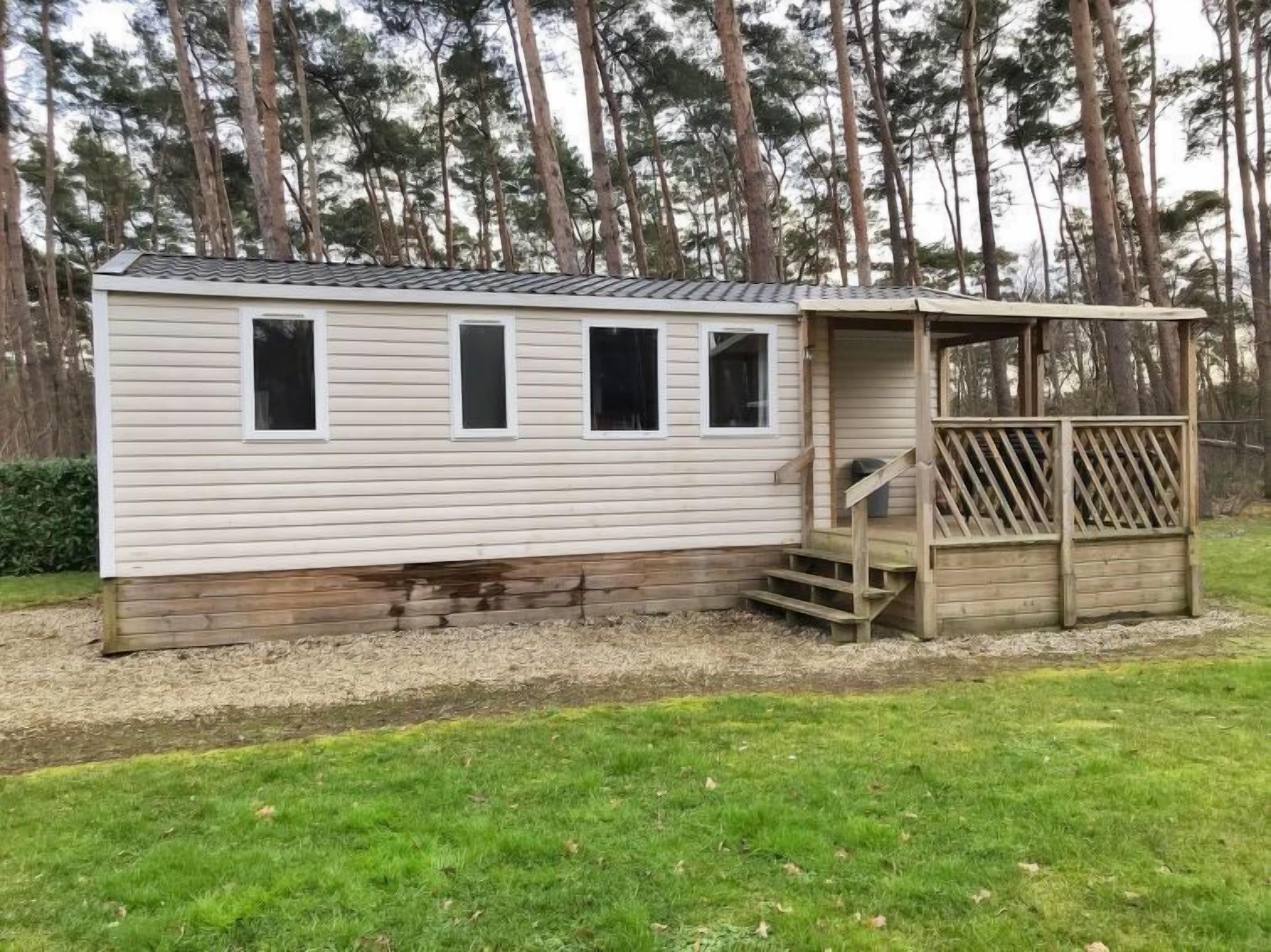 A single-story mobile home with a covered porch and a small set of stairs leading up to it.