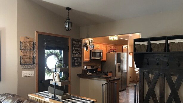 Een moderne keuken met een centraal eiland, een eetgedeelte met een geruit tafel, en een woonkamer met een leren bank.