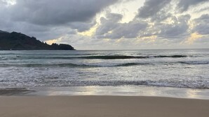 A beach with footprints in the sand and a cloudy sky.