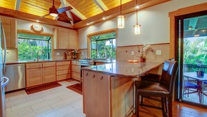 A modern kitchen with wooden cabinets, a central island, and pendant lighting.
