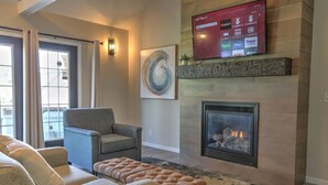 A living room with a fireplace, a mounted TV, and a comfortable seating area.