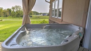 A hot tub on a porch with a view of a green landscape.