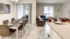 A modern living space with a dining area, kitchen, and seating area. - 4BR 3BA, Access 2 Waterparks, Private Pool, FREE Grill. Near Disney Orlando! (Davenport)