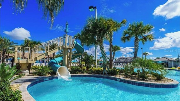 A swimming pool with a water slide, palm trees, and a clear blue sky. - 4BR 3BA, Access 2 Waterparks, Private Pool, FREE Grill. Near Disney Orlando! (Davenport)