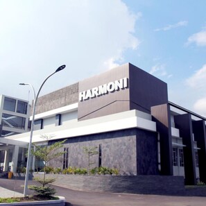 A modern building with a prominent 'HARMONI' sign, featuring a clean, geometric design with a mix of glass and concrete materials.