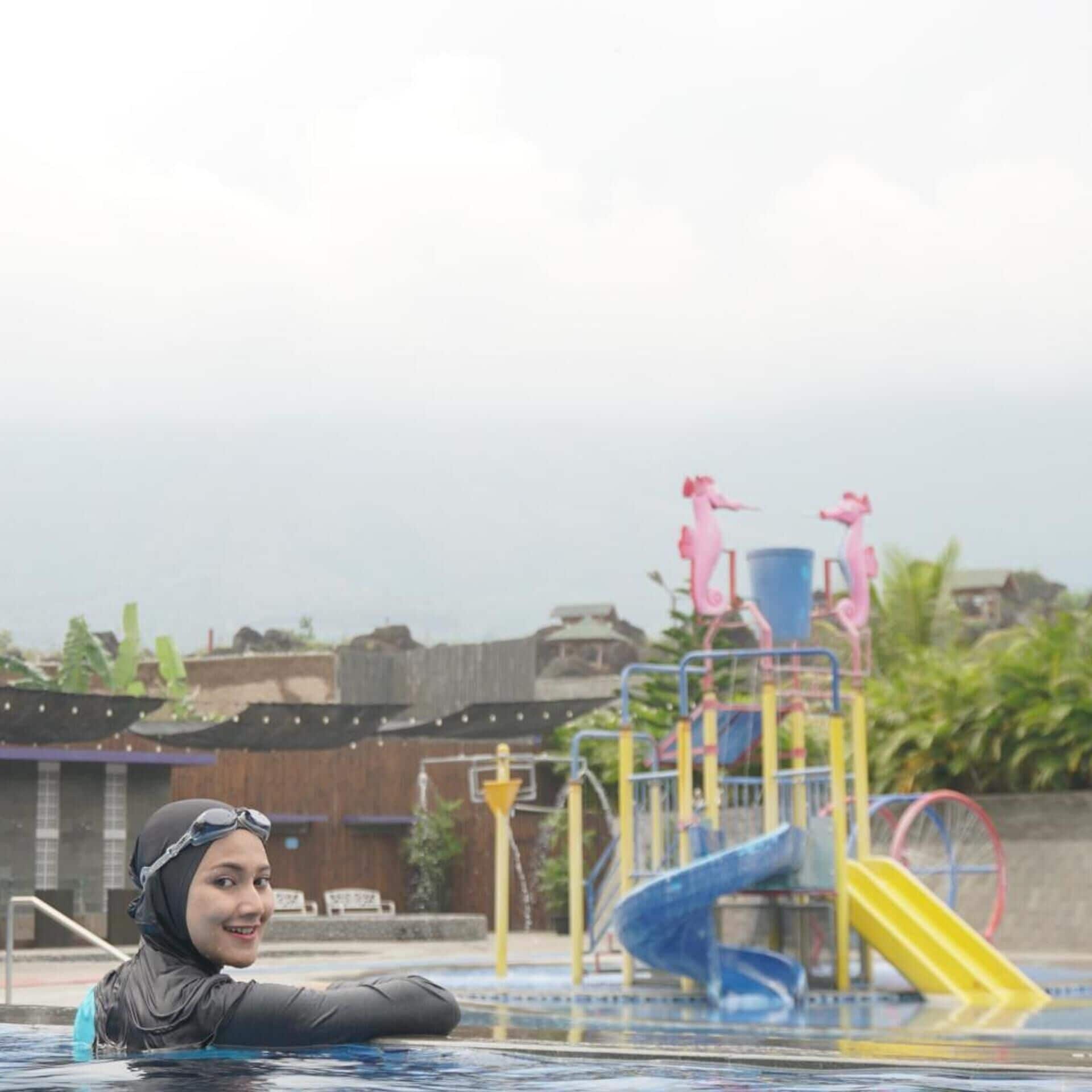 A swimming pool with a slide and a diving platform.