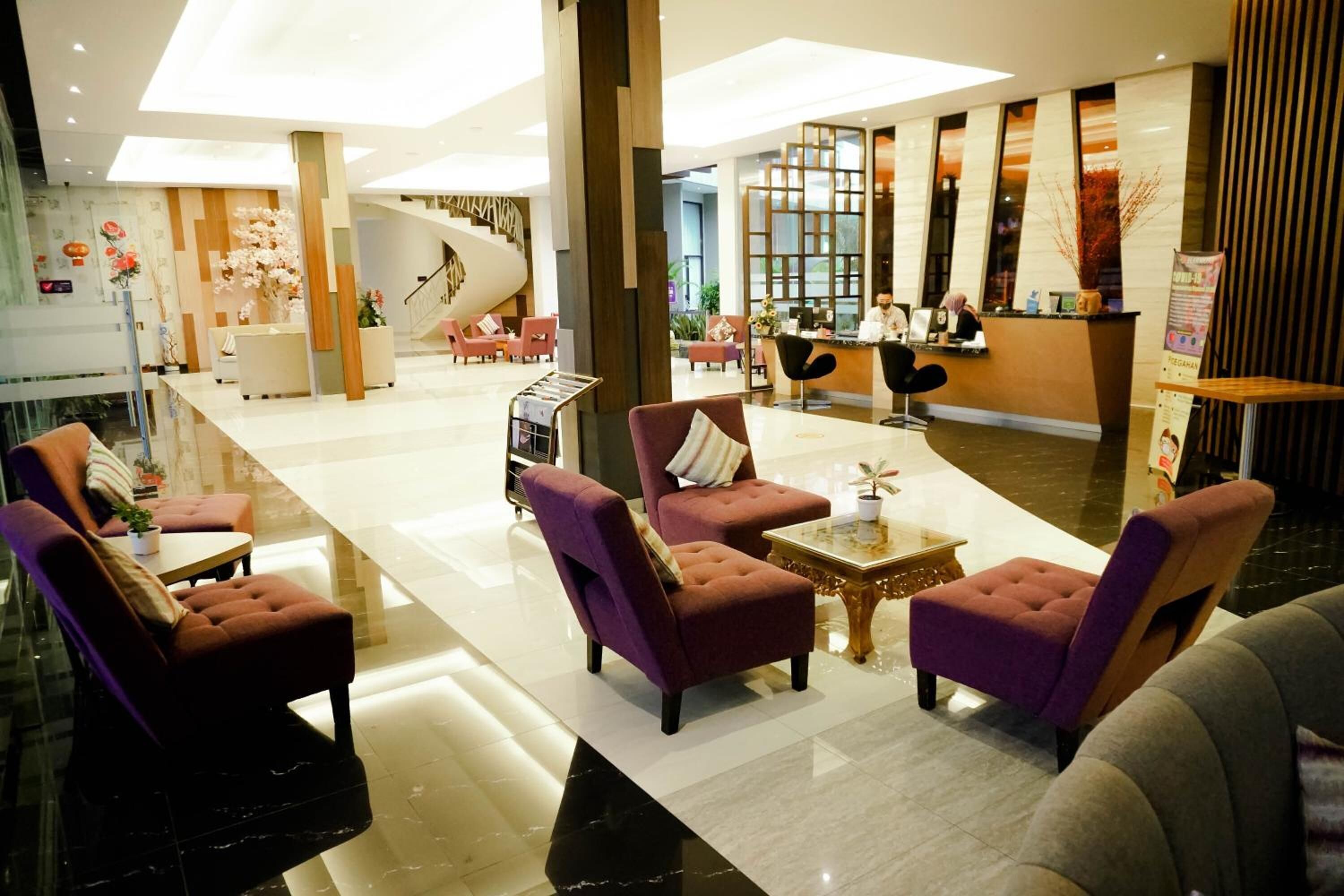 A spacious lobby with a reception desk, purple armchairs, and a staircase.