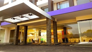 A modern building with a covered entrance, large windows, and stone pillars. - Harmoni Garut (Garut)