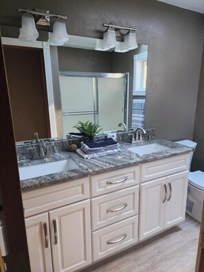 A bathroom with a double sink vanity, a large mirror, and a towel rack. - Quiet 4 bedroom Home with Hot Tub nestled in the woods (Springfield)