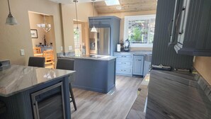 Een moderne keuken met een centraal eiland, geïntegreerde apparatuur en een eethoek met een tafel en stoelen.