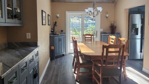 Een moderne keuken met een eethoek, met een houten plafond, inbouwmeubels, een roestvrijstalen koelkast en een grote eettafel met stoelen.