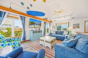 A spacious living room with a large sofa set, a coffee table, and a dining area. - Soundside Home w/ Private Pool, Game Room, Basketball, and Nearby Beach Access (Avon)