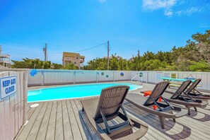 A pool area with lounge chairs, a pool, and a 'KEEP GATE CLOSED' sign.