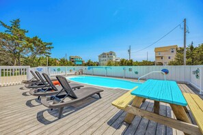 A pool area with lounge chairs and a picnic table.