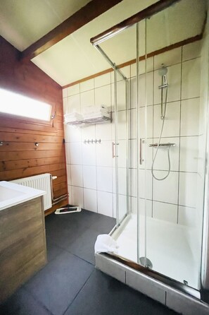 A modern bathroom with a glass-enclosed shower, white tiled walls, and a wooden ceiling. - De Brenkberg by Interhome (Schinveld)
