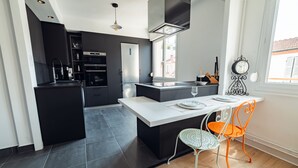 Una cocina moderna con armarios oscuros, una isla central y un comedor con mesa y sillas.