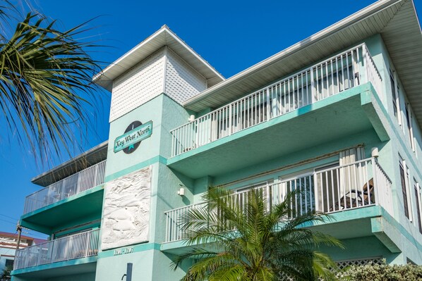 Un immeuble à plusieurs étages doté de balcons, une enseigne indiquant « West North » et un palmier au premier plan.