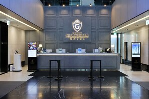 A hotel reception desk with a digital screen, a logo, and a sign indicating the Gloucester Hotel. - Gloucester Hotel Kintex (Goyang)