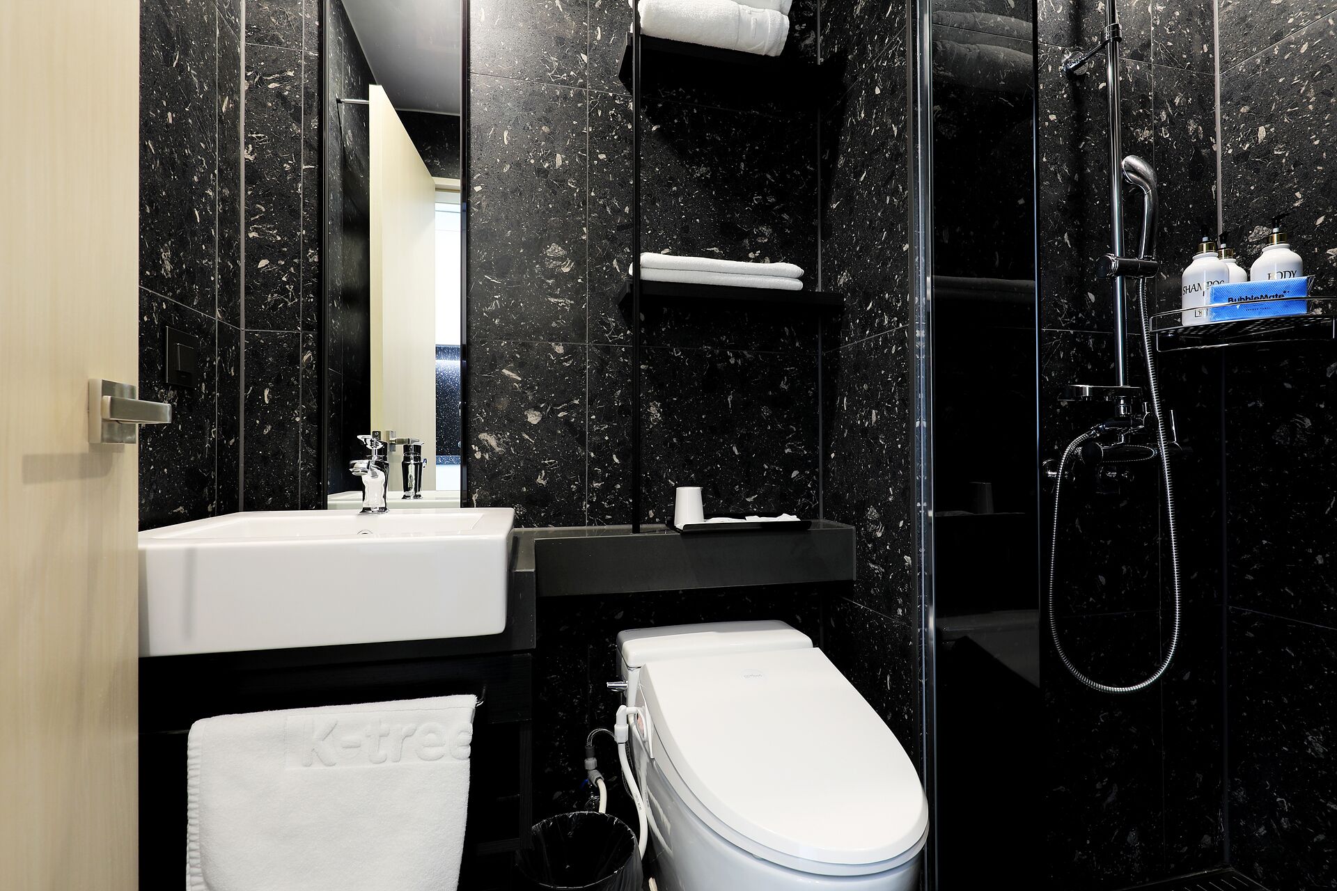 Une salle de bain moderne avec des toilettes blanches, un lavabo, un miroir et un espace douche.