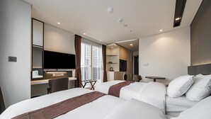 Habitación de hotel con dos camas grandes, un escritorio con silla, televisión y una mesita.