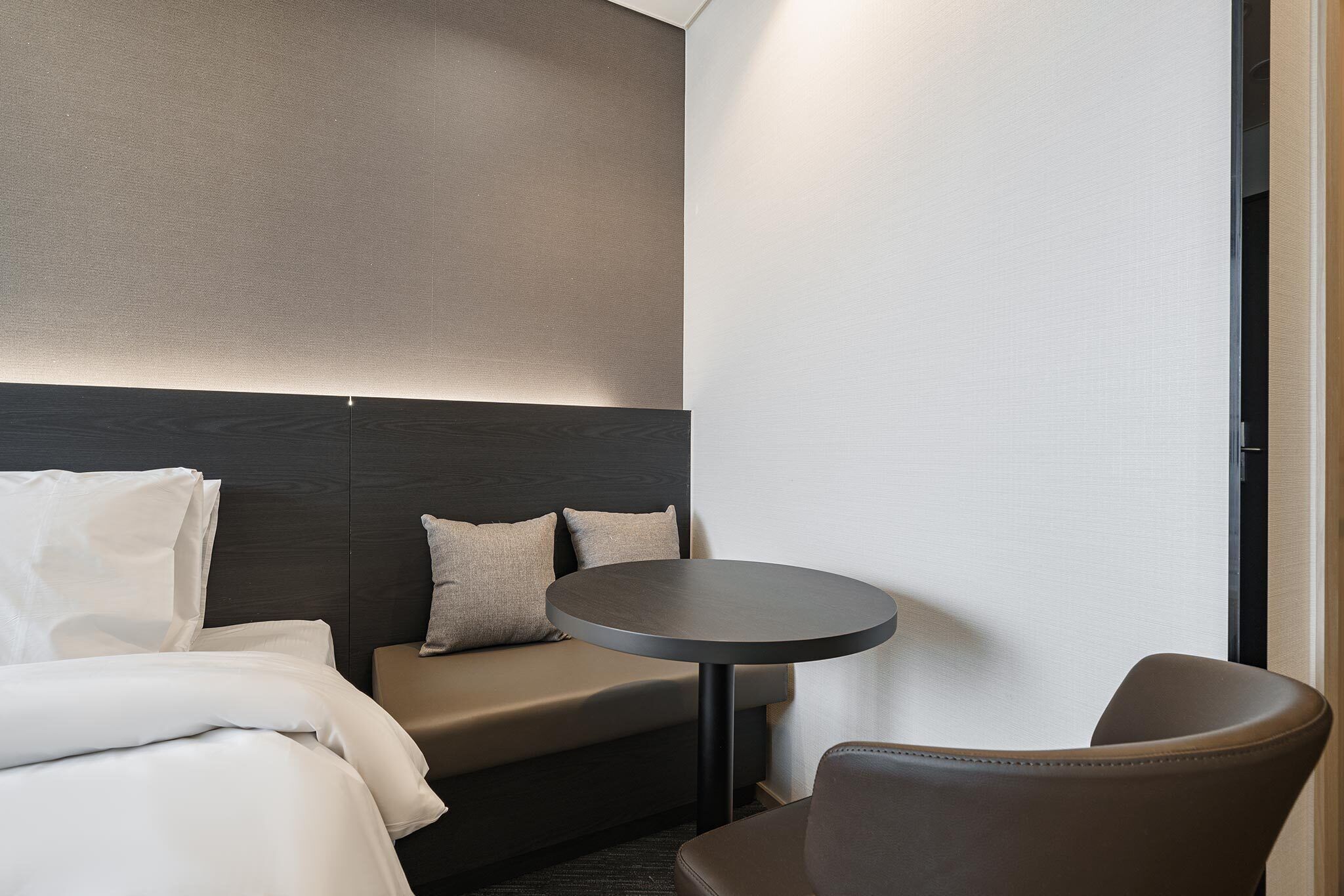 A modern hotel room with a bed, a sofa, a round table, and a chair.