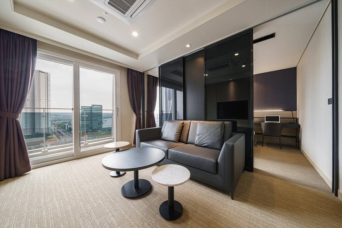 A modern living room with a sofa, two coffee tables, and a TV.