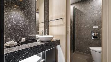 Un baño moderno con un espejo grande, un lavabo a la vista, un perchero y una zona de ducha.