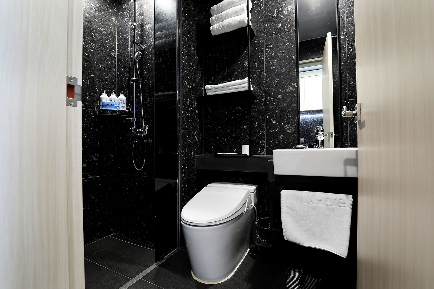 A modern bathroom with a shower, toilet, sink, and a towel rack.