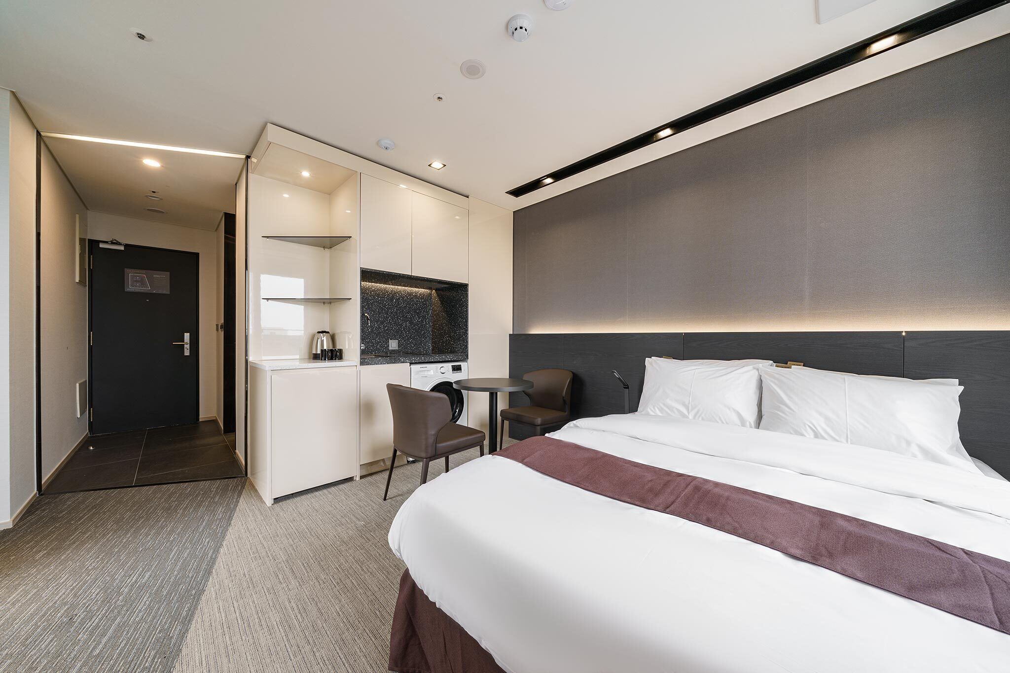 A modern hotel room with a large bed, a desk, and a seating area.