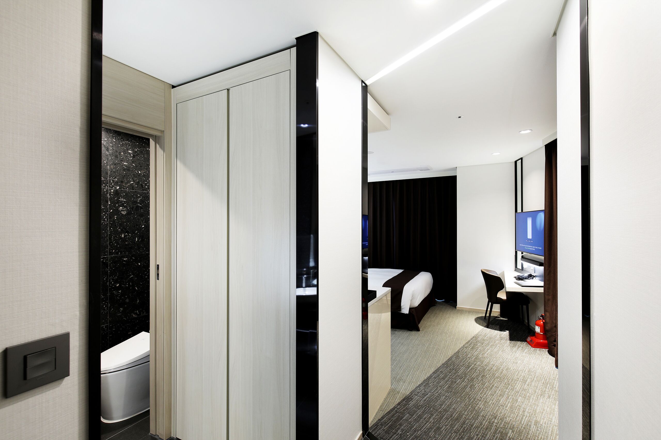 Une chambre d’hôtel équipée d’un lit, d’un bureau, d’une chaise, d’une télévision et d’une salle de bain avec des toilettes et un lavabo.