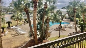 A pool area with palm trees, lounge chairs, and a small fountain.