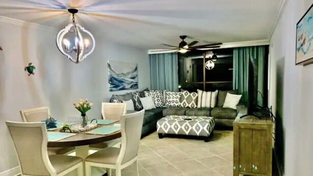 A dining area with a table and chairs, a sofa, and a ceiling fan.