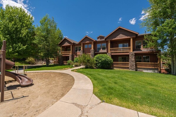 A multi-story building with a central courtyard, a playground, and a well-maintained lawn.