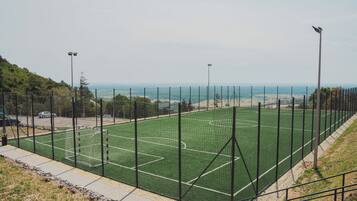 Un campo deportivo con porterías, rodeado de una valla y con iluminación artificial.