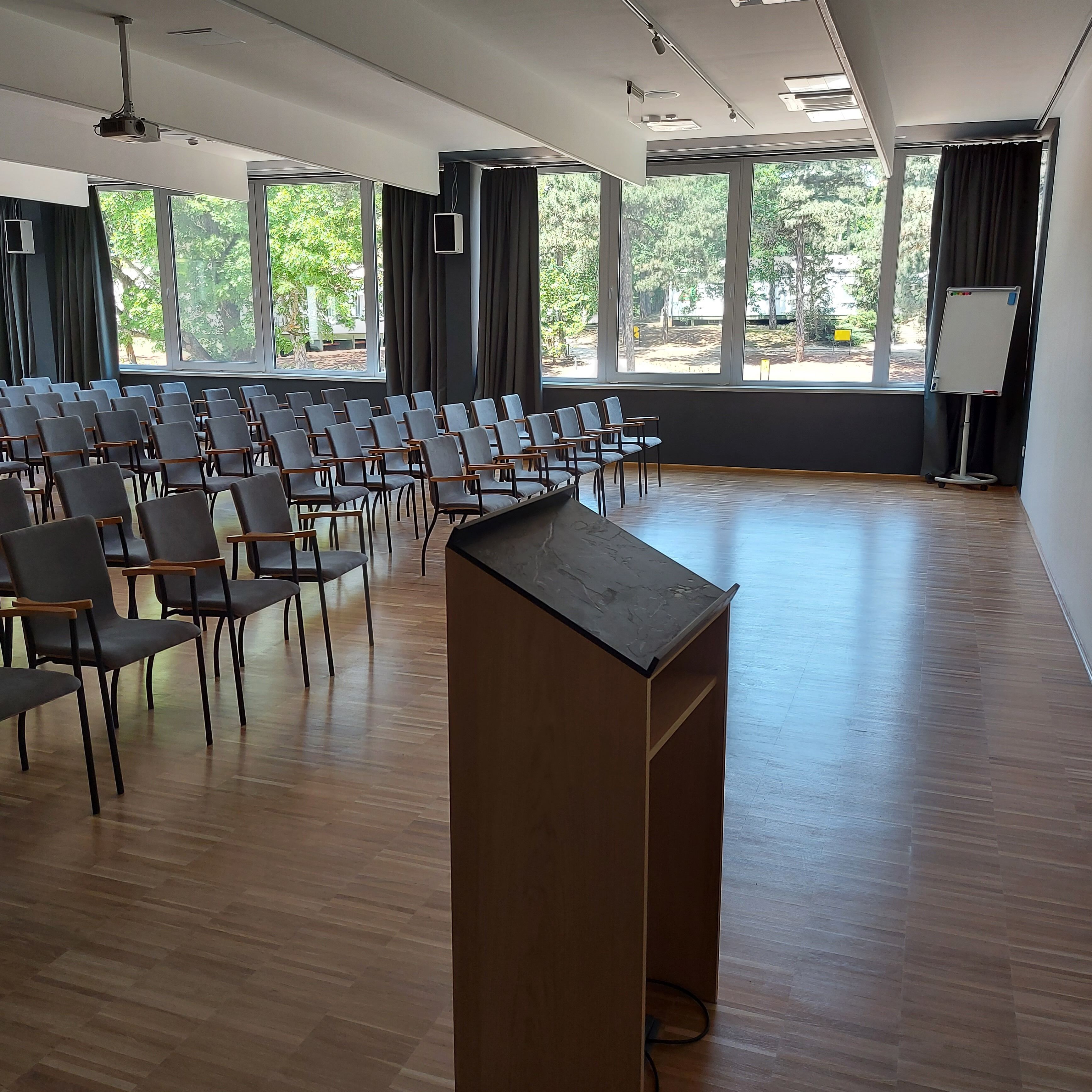 A conference room with rows of chairs, a podium, large windows, and a whiteboard.