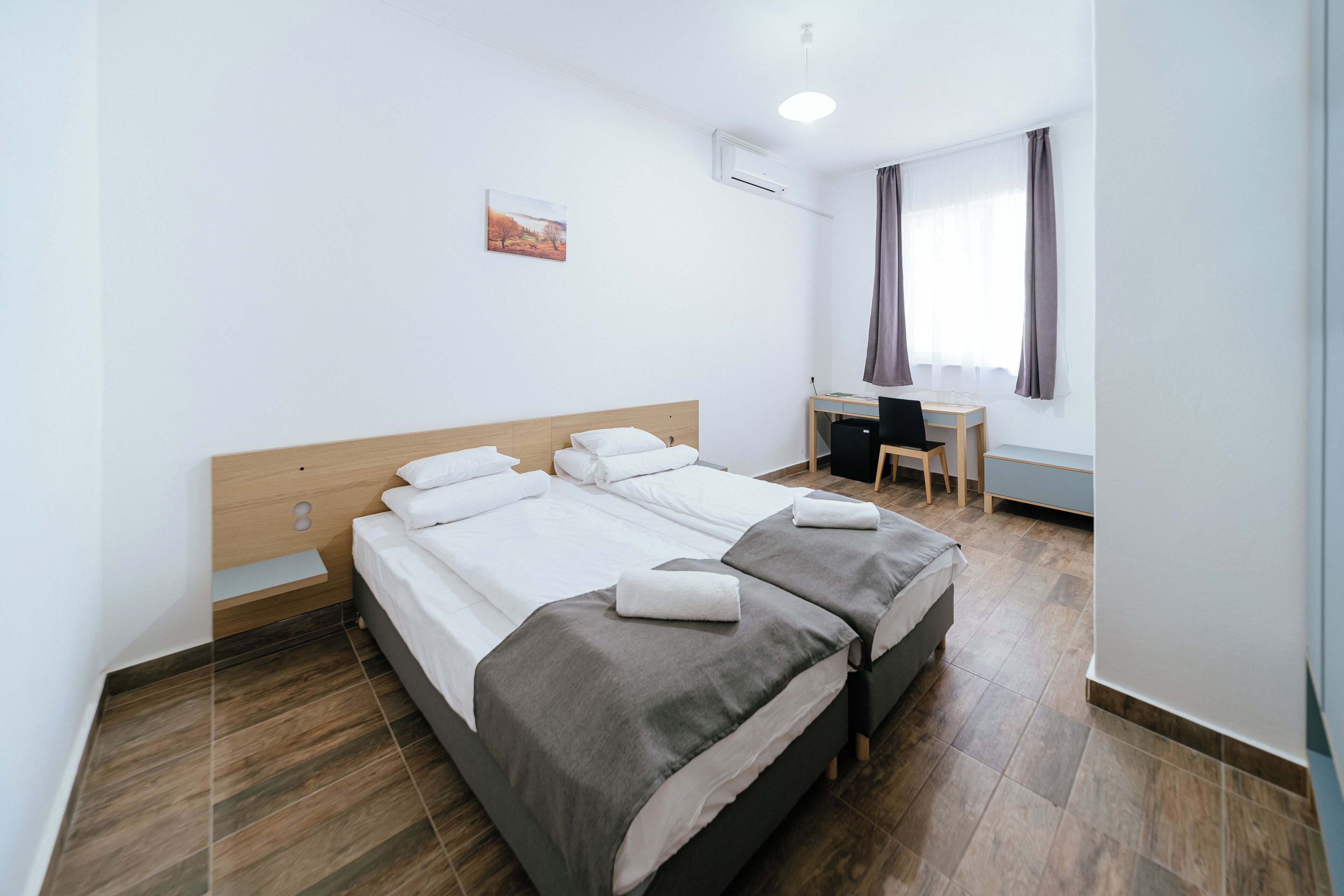 A hotel room with two beds, a desk, and a chair.