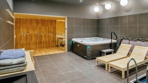 Ein moderner Wellnessraum mit Holzbiosauna, Whirlpool und zwei Liegen.