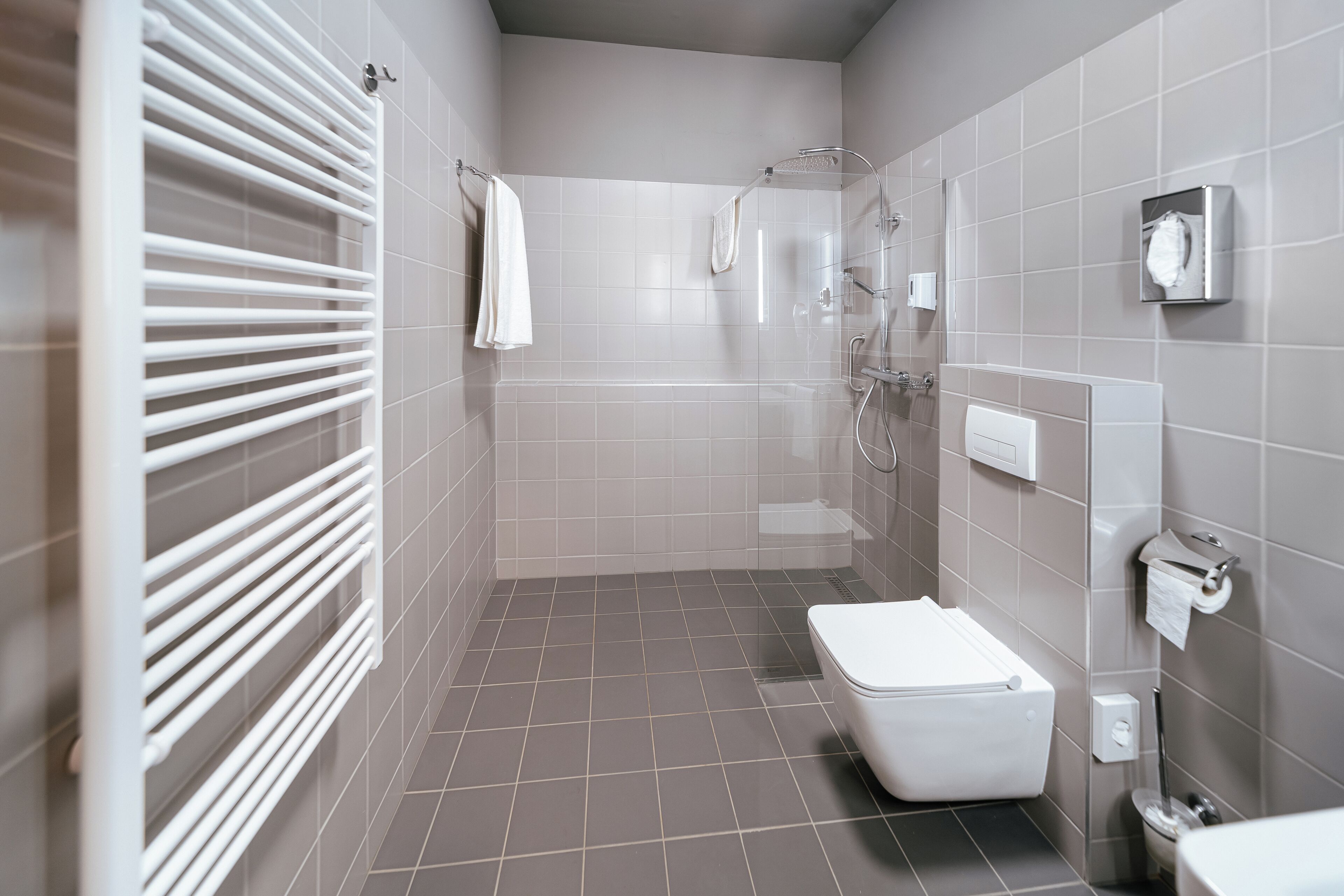 A modern bathroom with a toilet, shower, and towel rack.