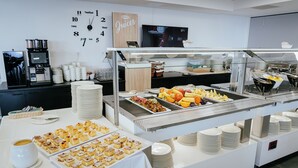 Ein Buffet mit verschiedenen Speisen, eine Kaffeestation und eine Uhr an der Wand.