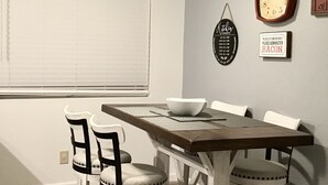 A dining area with a wooden table and four chairs, a ceiling fan, a clock, and a sign on the wall. - A Beautiful Colorado River Retreat (Bullhead City)