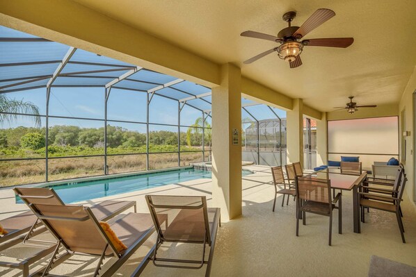 Relax by the pool with lounge chairs and a dining area, surrounded by lush greenery.