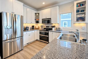 A modern kitchen with stainless steel appliances, white cabinetry, granite countertops, and a built-in oven. - Experience the island lifestyle, live like a local! 4Br/3.5ba waterfront duplex. (Wrightsville Beach)