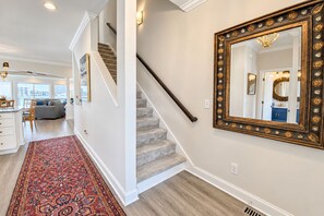 A staircase with a wooden handrail leading to a landing, a large ornate mirror on the wall, and a red patterned rug on the floor. - Experience the island lifestyle, live like a local! 4Br/3.5ba waterfront duplex. (Wrightsville Beach)