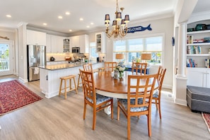 A modern kitchen with a central island, stainless steel appliances, and a chandelier.